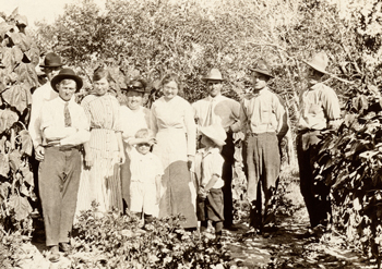 Old photo showing group of men women and children in rural setting